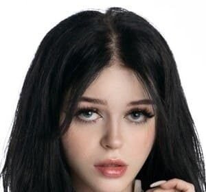 Nevaaadaa standing outdoors with long black hair wearing trendy black, white, and pink clothing.