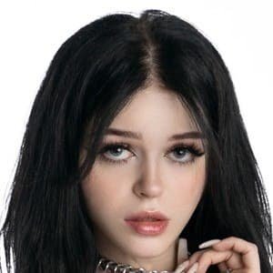 Nevaaadaa standing outdoors with long black hair wearing trendy black, white, and pink clothing.